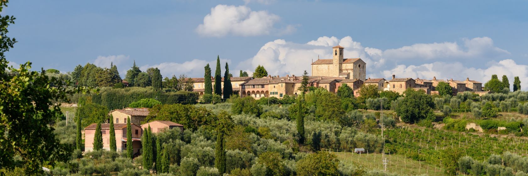 Klostret Certosa di Pontignano med odlingar och uppstickande cypresser i f�rgrunden.